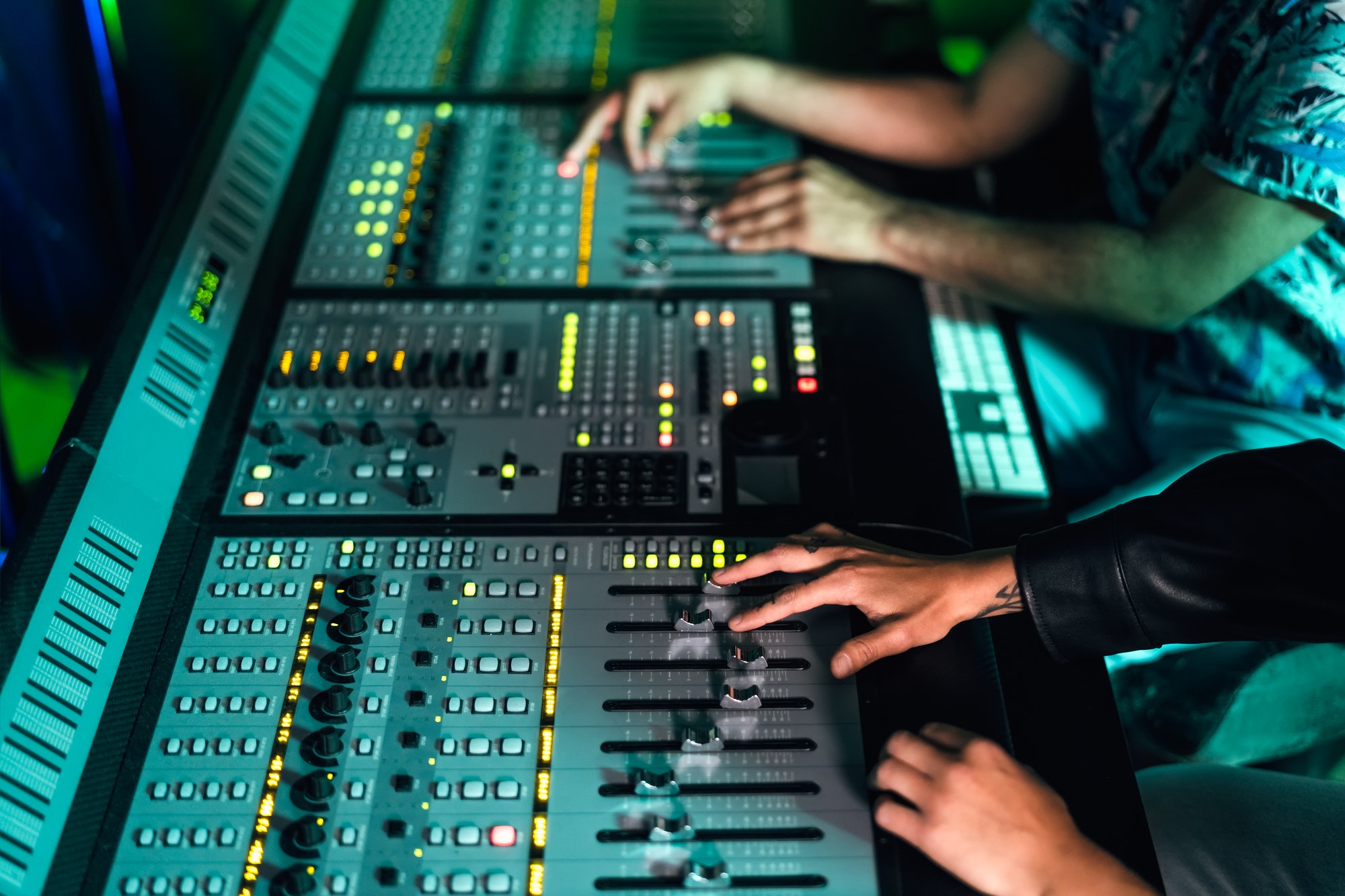 Close up audio engineer hands working with panel mixer control in music recording studio